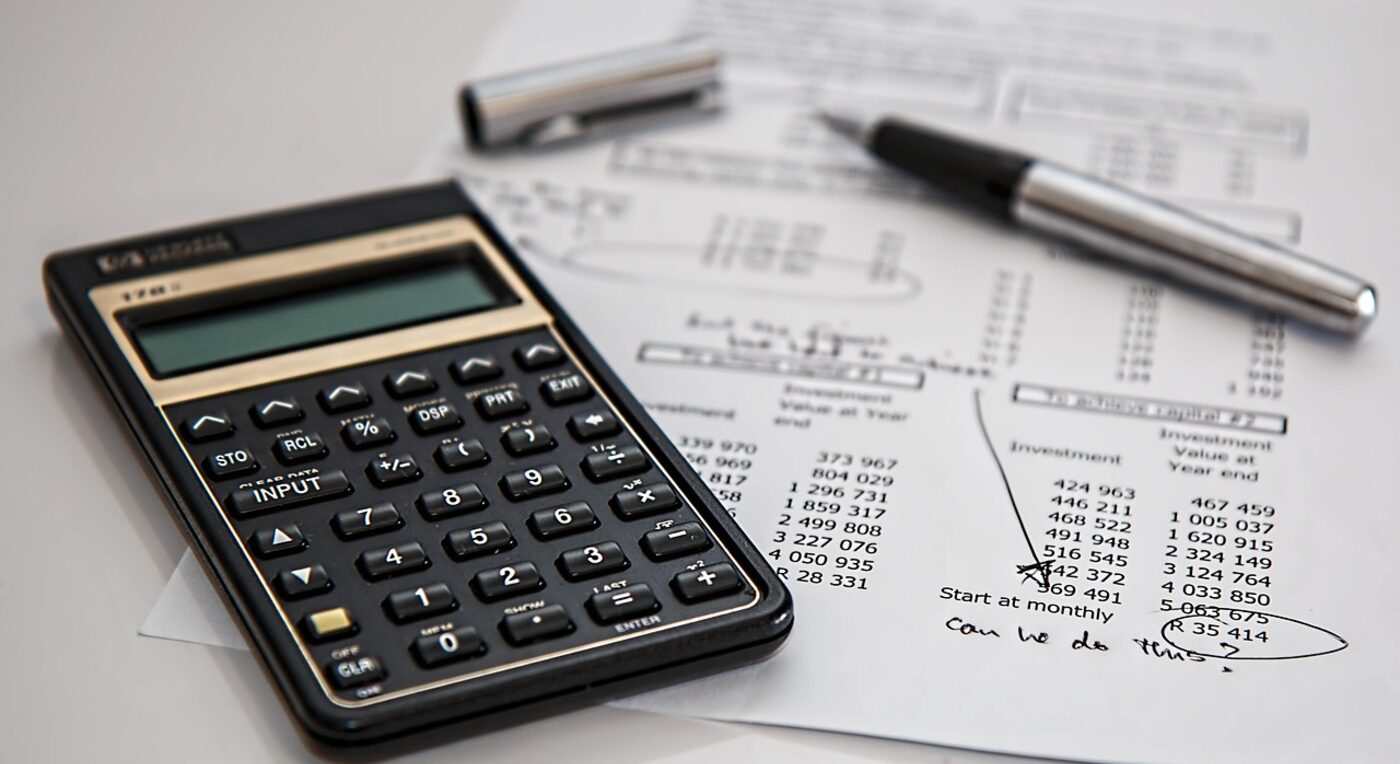 A calculator and financial documents on a desk — the free vs paid decision comes down to real numbers, not sticker price